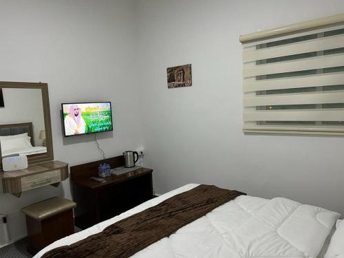 a bedroom with a bed and a flat screen tv at Petra Pass Hostel in Wadi Musa