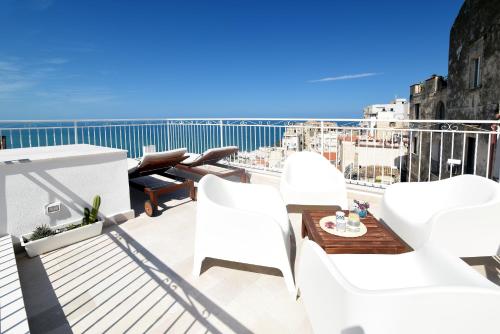 Un balcón con sillas blancas y vistas al océano. en Vico Lungo 9, Peschici en Peschici