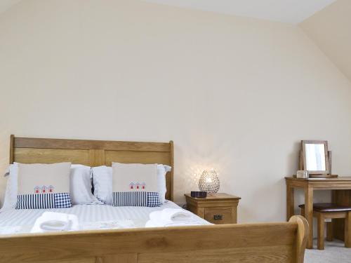 een slaapkamer met een houten bed met witte lakens en kussens bij Hedderwick House in Pittenweem