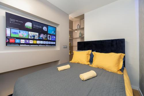 een slaapkamer met een bed met gele kussens en een flatscreen-tv bij Liberty in Zagreb
