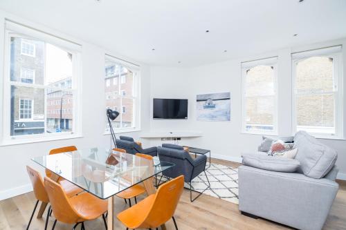 uma sala de estar com uma mesa de vidro e cadeiras em Whitfield Street Apartments em Londres