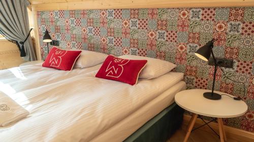 a bedroom with a bed with red pillows on it at Apartamenty Osada Biała Woda Szczawnica Jaworki in Szczawnica