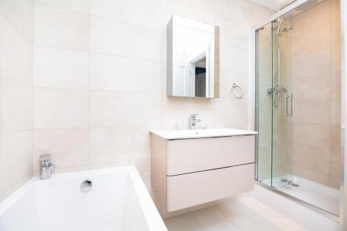 a white bathroom with a sink and a shower at Whitfield Street Apartments in London