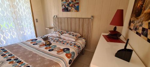 een kleine slaapkamer met een bed en een tafel met een lamp bij Au bout du lac d'Annecy in Doussard