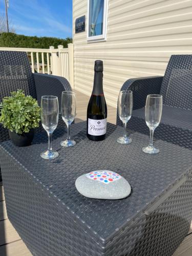 a bottle of wine sitting on a table with wine glasses at Haven - Hafan Y Mor (Pwllheli) in Pwllheli