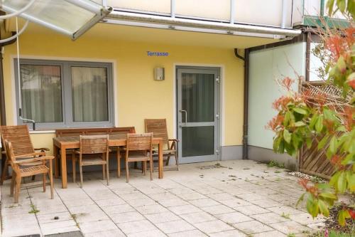 patio z drewnianym stołem i krzesłami w obiekcie Freundliche Wohnung mit Parkplatz und Terrasse w mieście Neubrandenburg