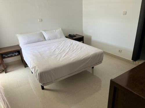 Bett mit weißer Bettwäsche und Kissen in einem Zimmer in der Unterkunft HOTEL NAKHIL in Nouadhibou