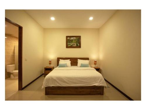 een slaapkamer met een bed met 2 nachtkastjes en een spiegel bij Dawn Light Villa, Sire in Tanjung