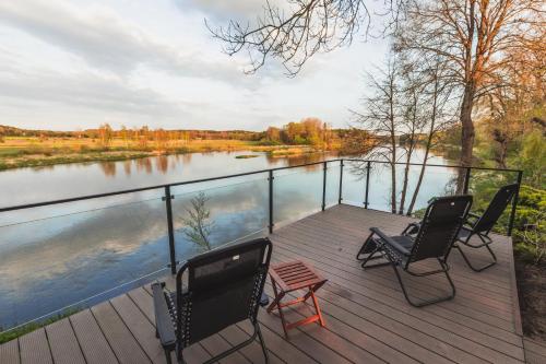 two chairs and a table on a deck next to a river at Dwór w Zabużu in Zabuże