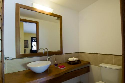 a bathroom with a sink and a mirror and a toilet at Casa Surucuá com localização espetacular frente à Praia do Centro de Pipa - 2 a 4 quartos suite in Pipa