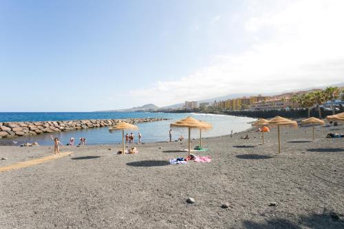 una spiaggia con ombrelloni e persone sulla sabbia di Precioso apartamento renovado en Candelaria a Candelaria