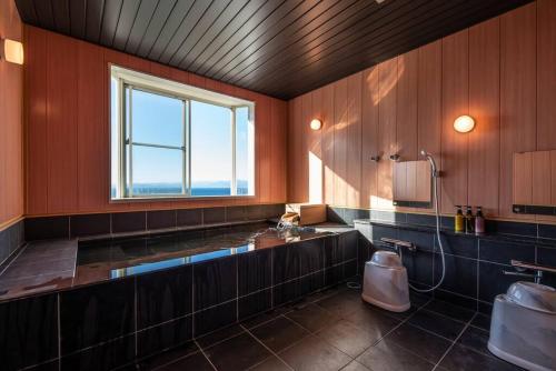 ein großes Bad mit einem Waschbecken und einem Fenster in der Unterkunft BLUE LAGOON in Numazu