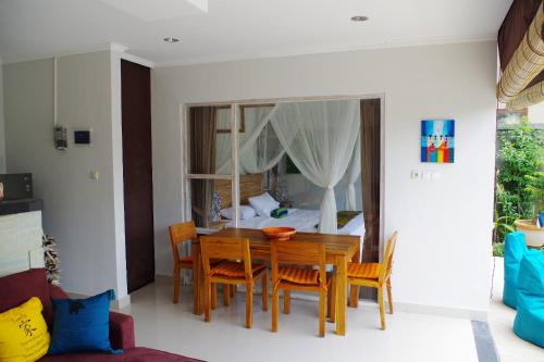 a dining room with a table and chairs and a bed at Ratna Villa in Ubud