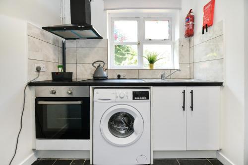 a kitchen with a washing machine and a sink at Laud Close Guest Suites in Reading