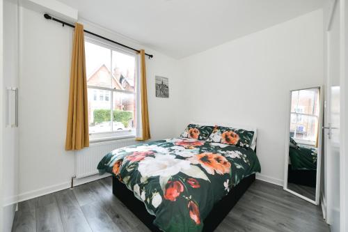 una camera da letto con un letto con un piumone floreale e una finestra di Waylen Street Suites a Reading