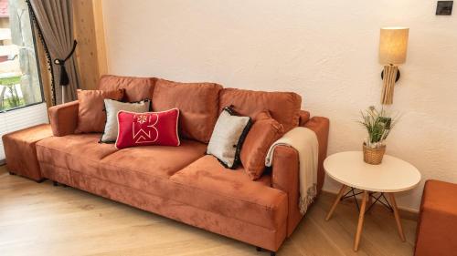 a brown couch with pillows on it in a living room at Apartamenty Osada Biała Woda Szczawnica Jaworki in Szczawnica