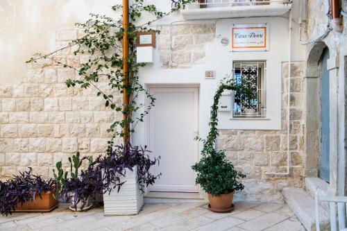 a white door in a stone building with potted plants at B&B Casa Dorsi in Polignano a Mare