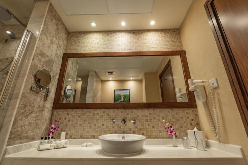 a bathroom with a sink and a large mirror at Elite Byblos Hotel in Dubai