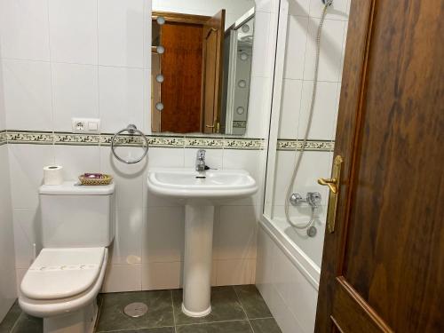 uma casa de banho com um lavatório, um WC e um espelho. em Hostal Restaurante La Curva em Adra