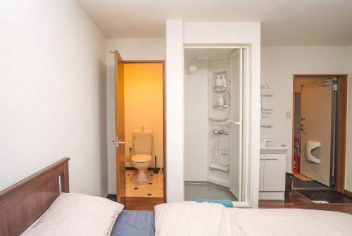 ein Schlafzimmer mit einem Bett und ein Badezimmer mit einem WC in der Unterkunft 庵・花園北 in Osaka