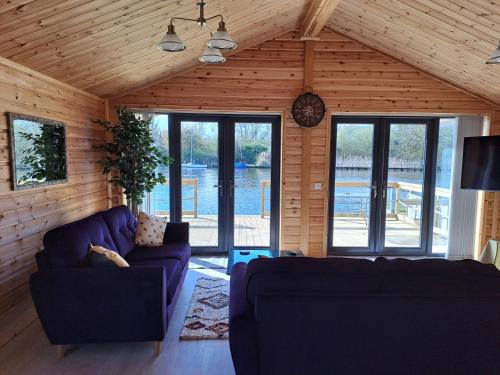 uma sala de estar com dois sofás azuis e janelas em Nature's Nook - Norfolk Broads em Brundall
