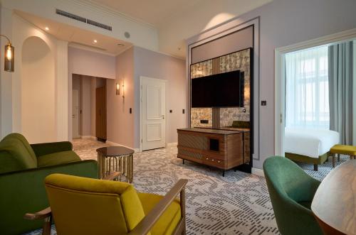 a living room with a couch and a bed and a television at Hotel Saski Krakow Curio Collection by Hilton in Krakow
