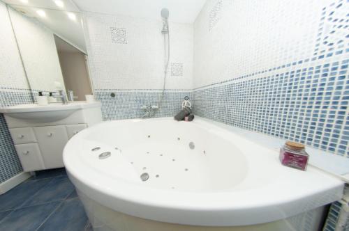 a white bath tub in a bathroom with blue tiles at MAGNOLIA-6 Min de la Gare - Baignoire Balnéo- Wifi Gratuit in Melun
