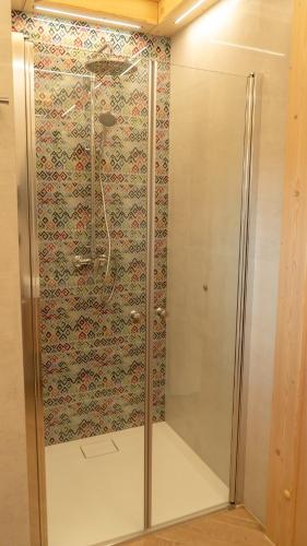 a shower in a bathroom with a patterned wall at Apartamenty Osada Biała Woda Szczawnica Jaworki in Szczawnica