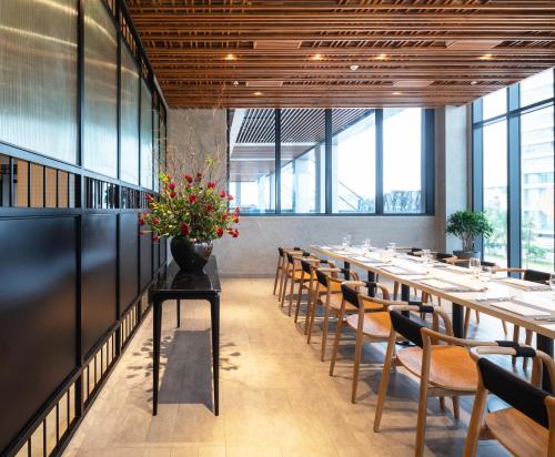 a long dining room with tables and chairs and a vase of flowers at Anya Hotel Quy Nhon in Quy Nhon