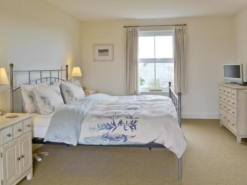 a bedroom with a bed with a television and a window at Little Stretton in Bigbury on Sea