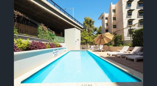 una piscina con sombrilla y sillas y un edificio en 501 Sky High Cbd Style With Parkingpool en Perth