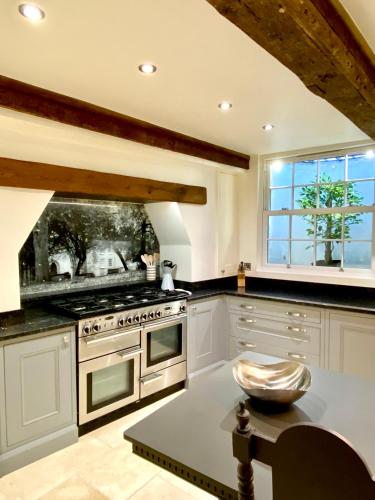 a kitchen with white cabinets and an oven and a table at Superbly Located Handsome Georgian Townhouse - Pass the Keys in Shrewsbury