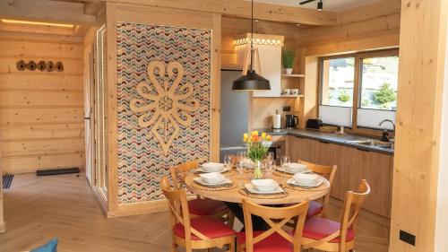 a dining room with a table and chairs and a kitchen at Apartamenty Osada Biała Woda Szczawnica Jaworki in Szczawnica