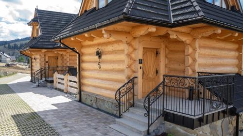 a log cabin with a staircase leading to a door at Apartamenty Osada Biała Woda Szczawnica Jaworki in Szczawnica