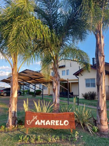 a sign in front of a house with palm trees at Complejo Amarelo in Chajarí