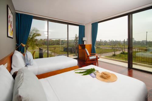 a hotel room with two beds and a balcony at Hola Villa 1 by Ovui in Hoi An