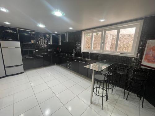 a kitchen with black cabinets and a white tile floor at Casa com vista pro Cristo Redentor in Niterói