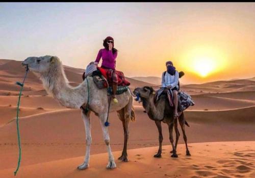 two people riding on the camel in the desert at Merzouga best camp in Merzouga