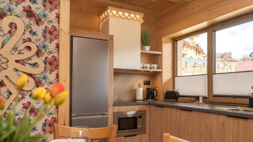 a kitchen with a stainless steel refrigerator and a window at Apartamenty Osada Biała Woda Szczawnica Jaworki in Szczawnica