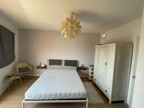 ein Schlafzimmer mit einem weißen Bett und einem Kronleuchter in der Unterkunft CASA NENO in La Mareta
