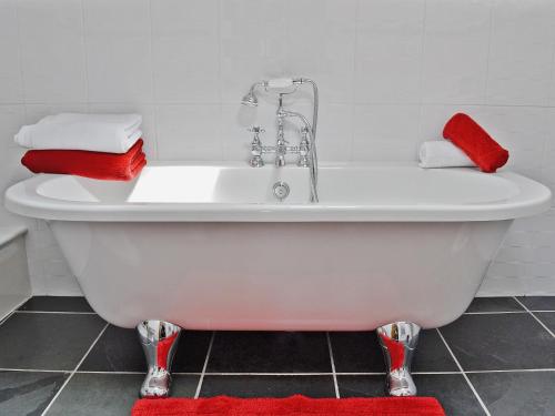 d'une baignoire blanche avec des serviettes rouges. dans l'établissement Hen Dy, à Eglwys-Fâch