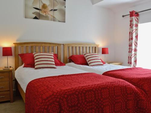 2 Betten in einem Schlafzimmer mit roter und weißer Bettwäsche in der Unterkunft Hen Dy in Eglwys-Fâch