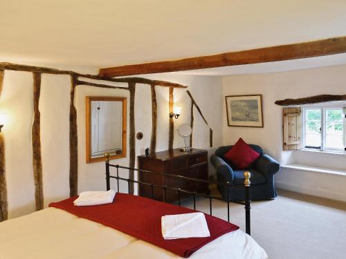 a bedroom with a bed and a chair at Syncocks Farm in Petrockstow