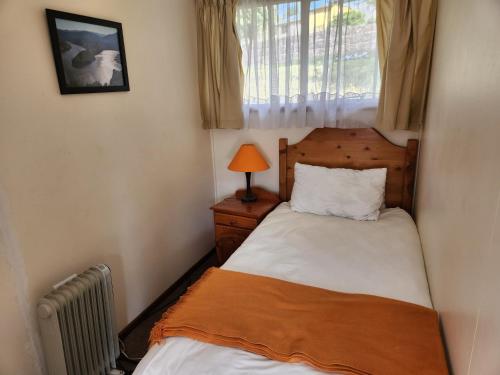 a small bedroom with a bed and a window at Motebong Lodge in Bokong