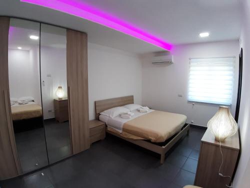 1 dormitorio con cama y luz rosa en Quiero Más B&B en San Nicola Arcella