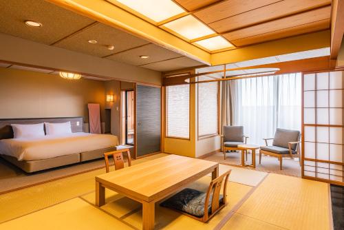 a bedroom with a bed and a table in a room at Atarayo Nishiizu Onsen in Izu