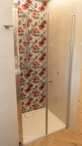 a shower stall in a bathroom with a floral wallpaper at Apartamenty Osada Biała Woda Szczawnica Jaworki in Szczawnica