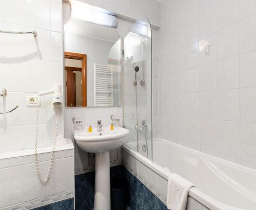 La salle de bains blanche est pourvue d'un lavabo et d'une douche. dans l'établissement Hotel Excelsior, à Timişoara
