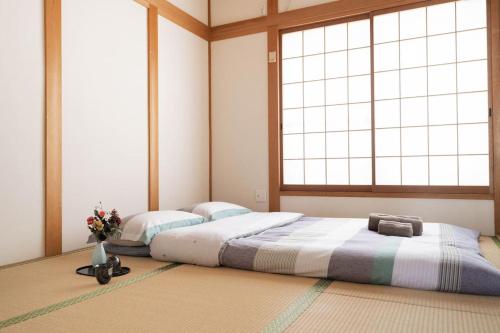 two beds in a room with two windows at 悠の宿 in Osaka