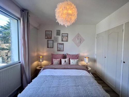 een slaapkamer met een groot bed en een kroonluchter bij Casa Bert - Moderne & Design T2 - Centre Ville - Parking Gratuit in Brive-la-Gaillarde